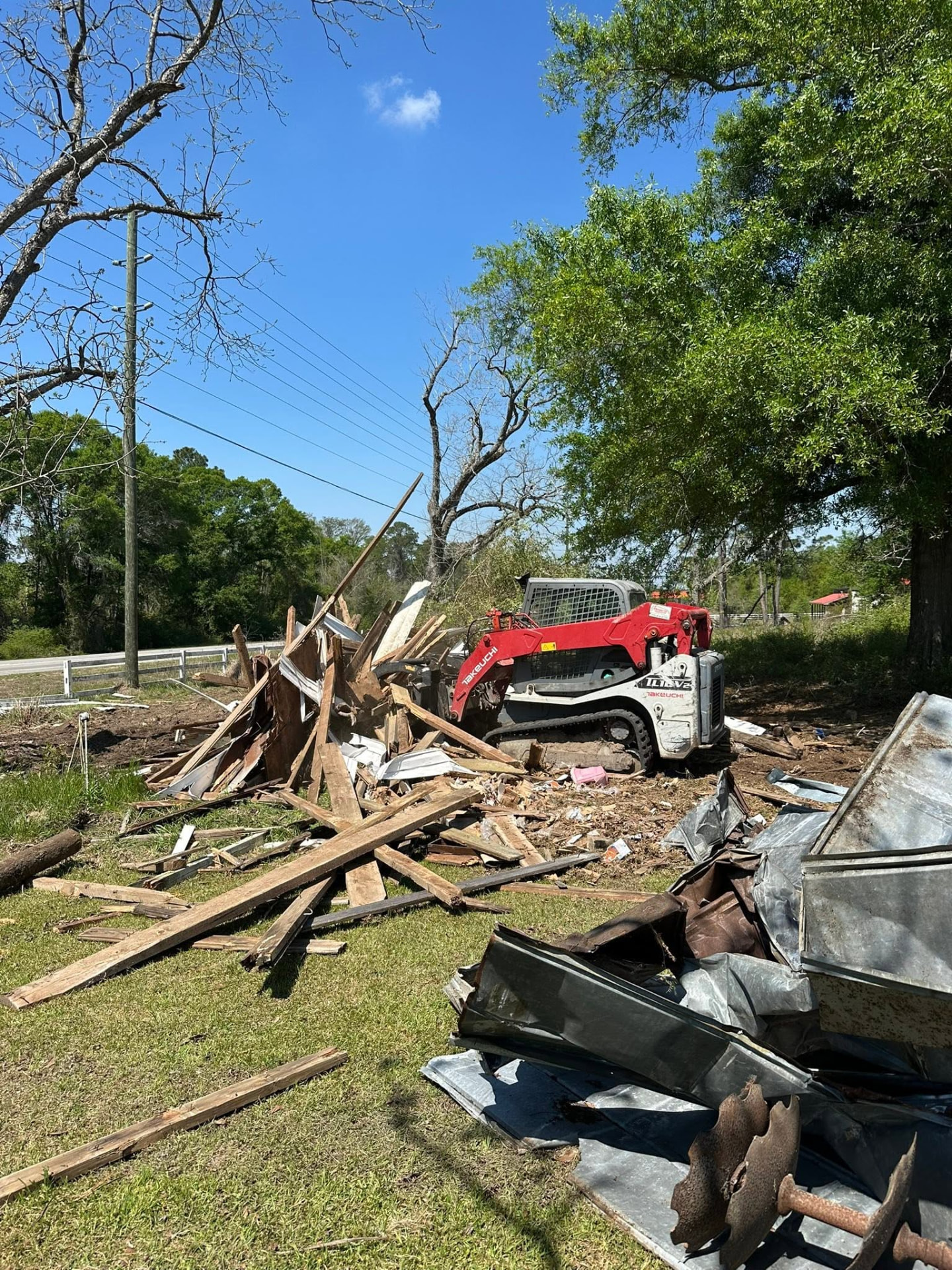 Track loader clearing demolition debris from a lot